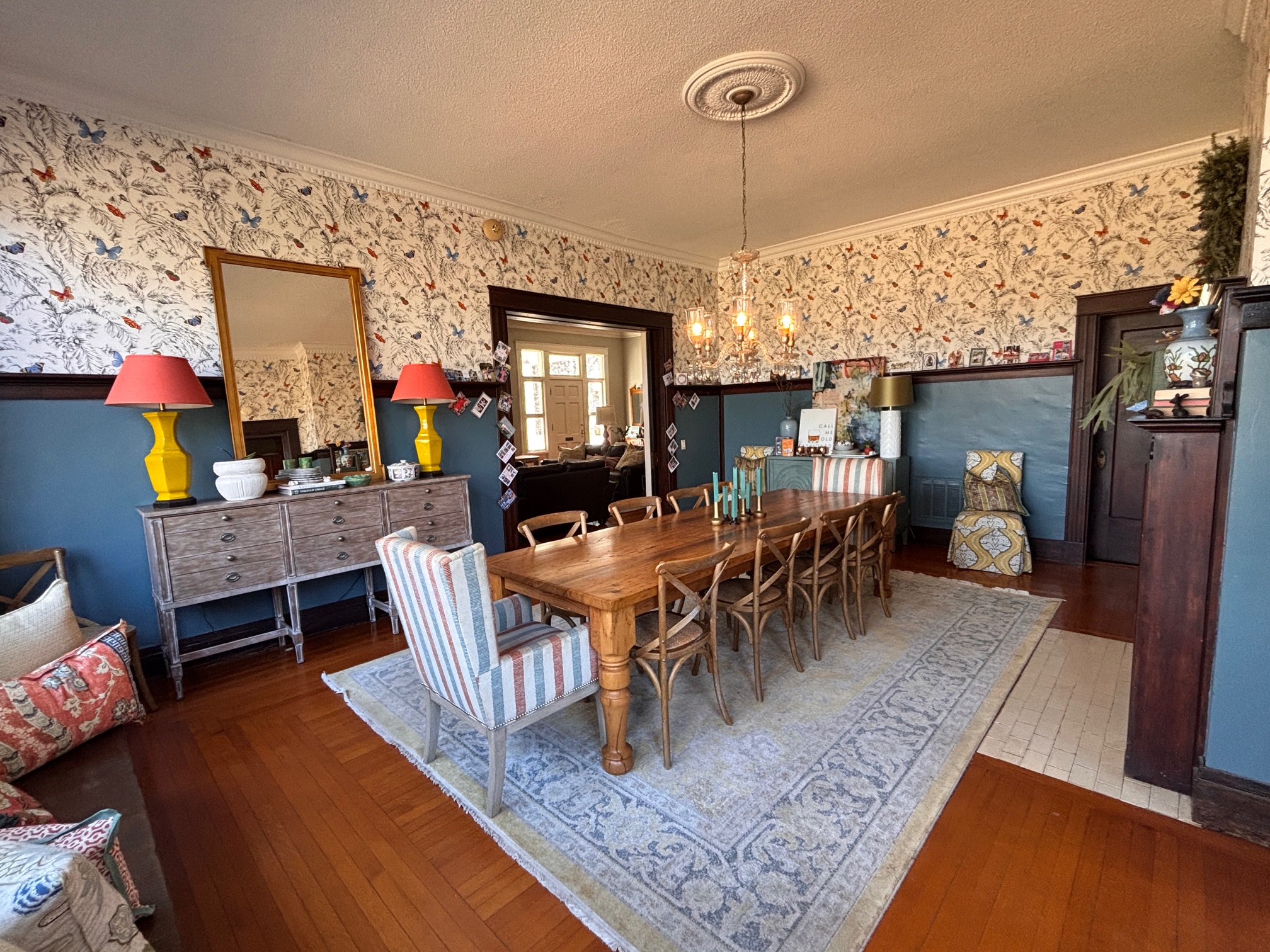 Elegant dining room with chandelier, gold mirror, and bird wallpaper at The Franklin House
